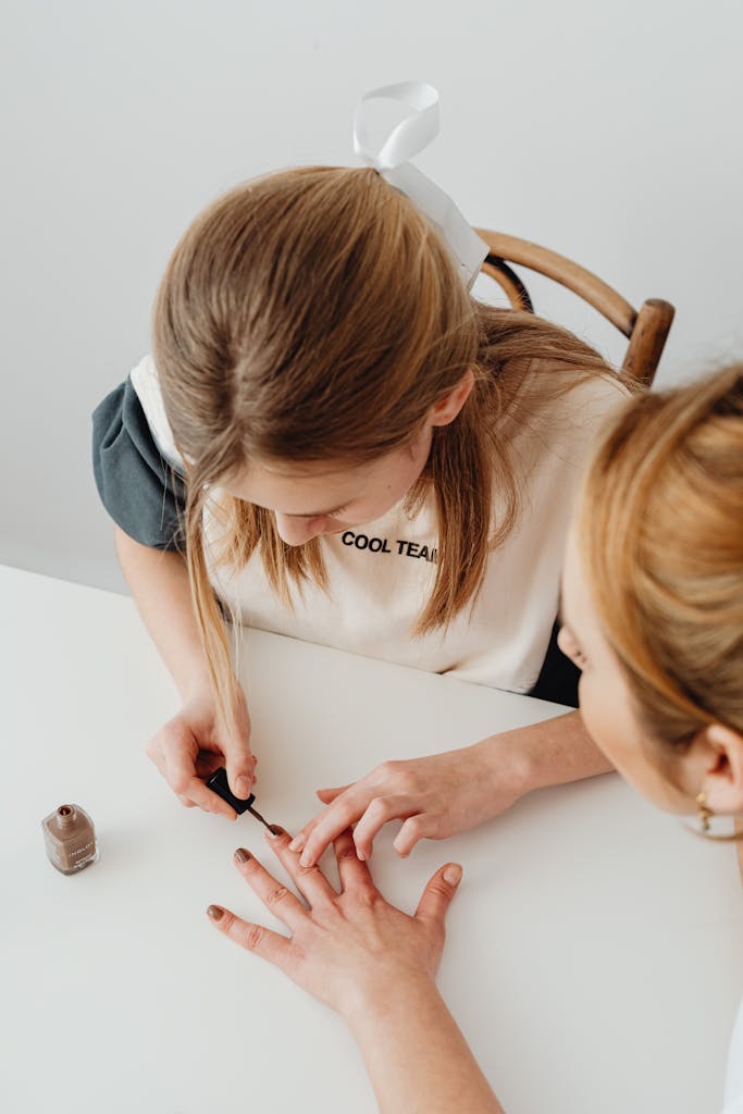 Young girl carefully applying nail polish, showcasing beauty and self-care indoors.